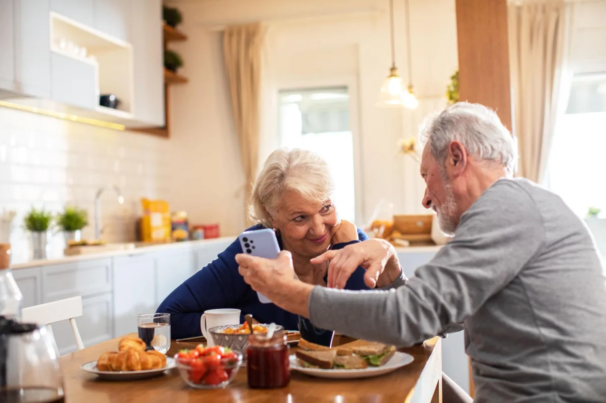 Older couple at the breakfast table, discovering the Amara app together