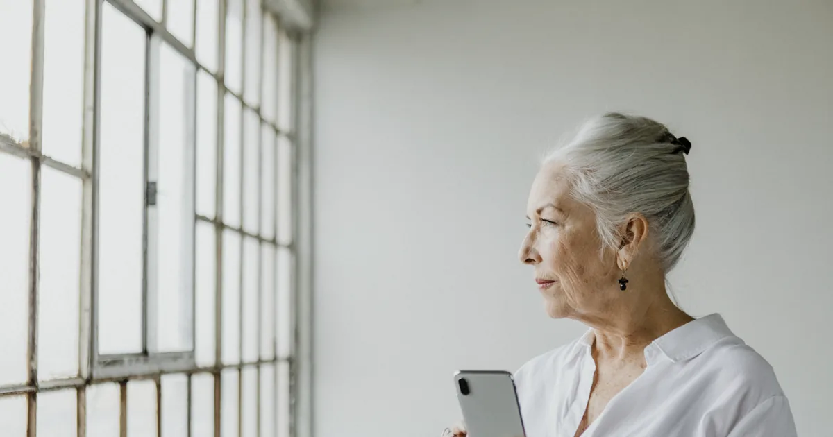 Adult child on the phone with their elderly parent, thinking about ways to support them from a distance